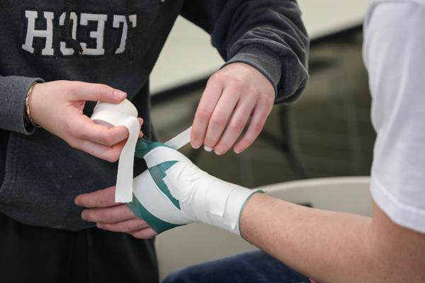 Student applying sports tape to a hand